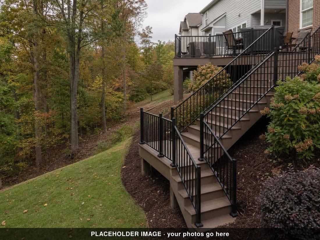 Composite deck stairs with black metal railing descending a wooded hillside in autumn (placeholder image)